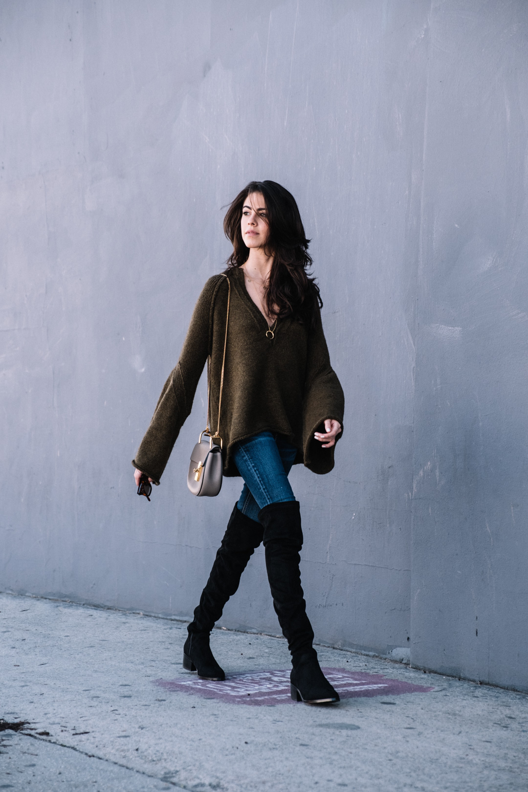 Jackie Roque styling a free people bell sleeve sweater, rag and bone jeans, over the knee boots and a gorjana necklace.
