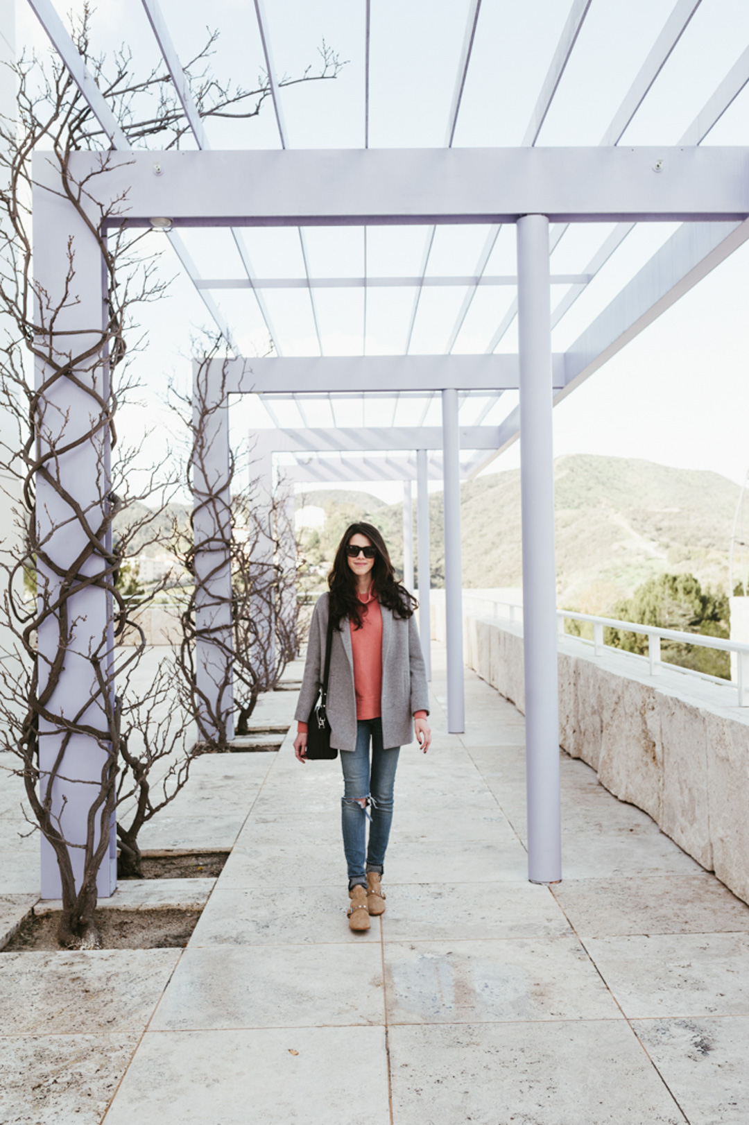 Jackie Roque styling a Madewell sweater, grey wool coat, Rag and Bone ripped jeans, Rebecca Minkoff Abigail Booties and Celine sunglasses at The Getty Museum in LA