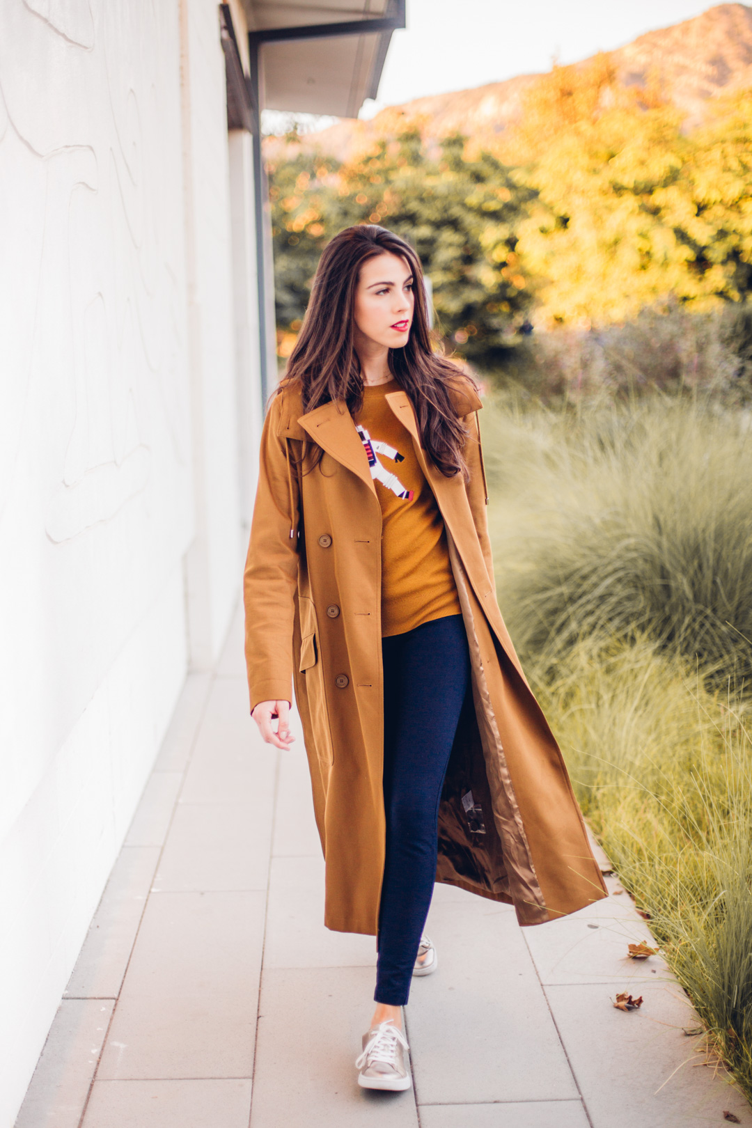 Jackie Roque styling a Lacoste Fall 2017 look with a brown trench coat and astronaut sweater in Malibu.